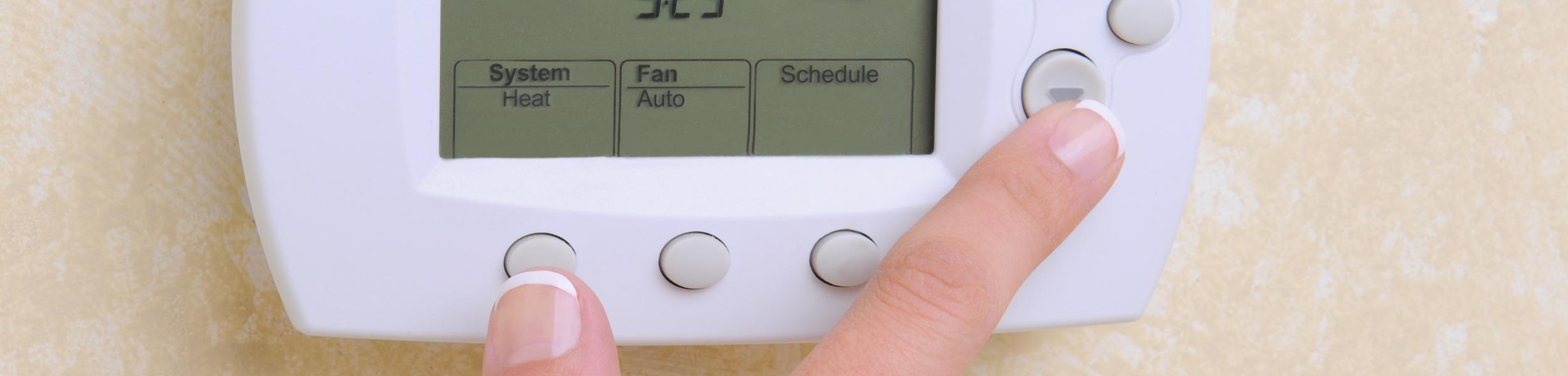 image of a person using a thermostat
